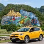 Taxi de La Habana a Viñales: taxi amarillo moderno frente al Mural de la Prehistoria